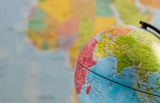 Close-up of a desktop globe showing Asia and Africa against a blurred world map background.