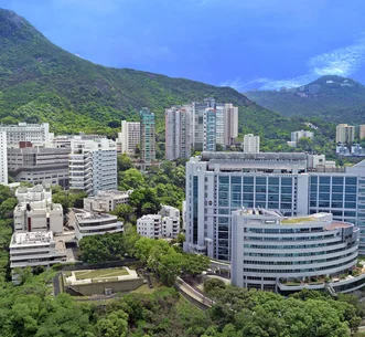 Panoramic view of HKU Li Ka Shing Faculty of Medicine campus on Sassoon Road nestled against lush green mountains under a clear blue sky.