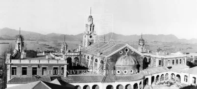 Elevated historical black-and-white photograph of the HKU Main Building complex and clock tower, with Victoria Harbour and hills in the background.