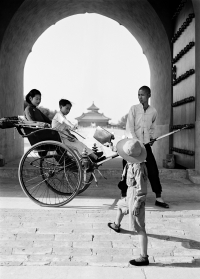 Bag being passed to a mother and child in a rickshaw.